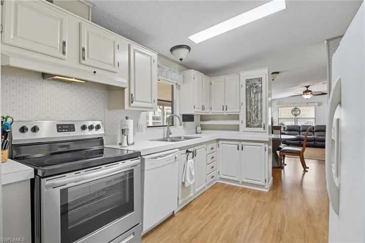 Kitchen featuring white appliances, light countertops, under cabinet range hood, light wood-style floors, and ceiling fan