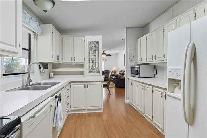 Kitchen with light countertops, stainless steel appliances, light wood finished floors, white cabinets, and a ceiling fan