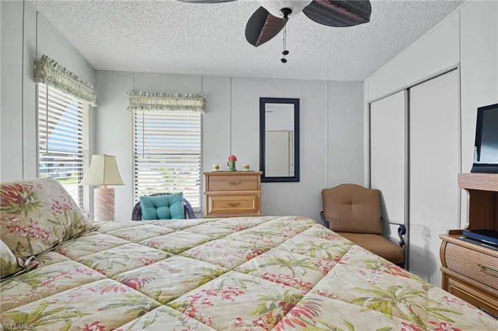 Bedroom featuring a closet, a textured ceiling, a ceiling fan, and a decorative wall