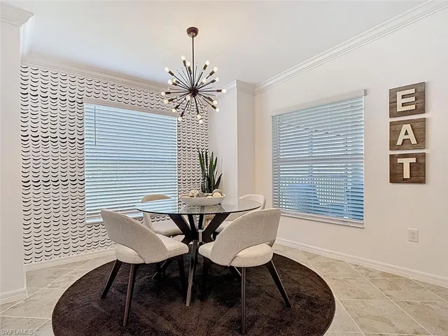 Dining room with crown molding, a chandelier, and light tile patterned flooring