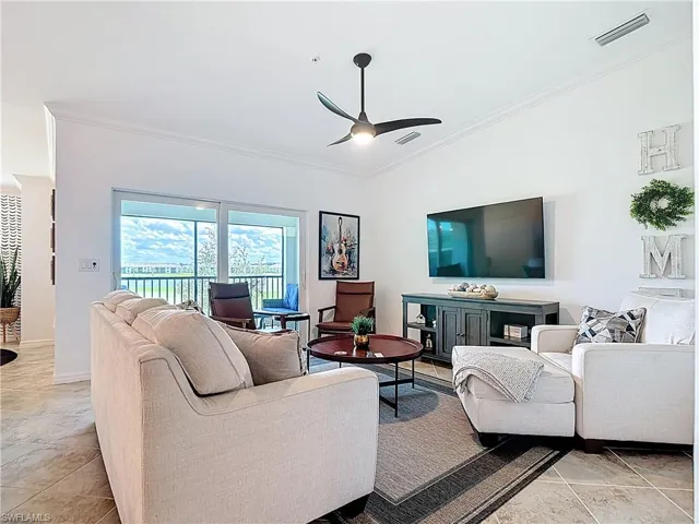 Living room featuring ornamental molding, vaulted ceiling, a ceiling fan, and light tile patterned flooring