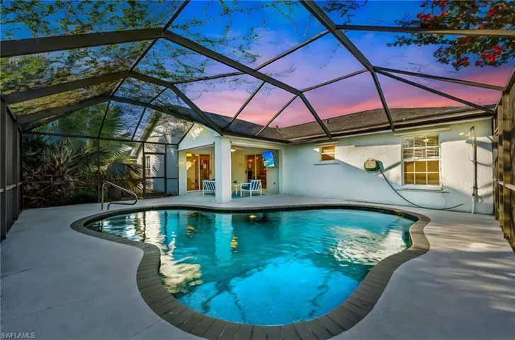 Outdoor pool featuring a sunroom, a patio area, and glass enclosure