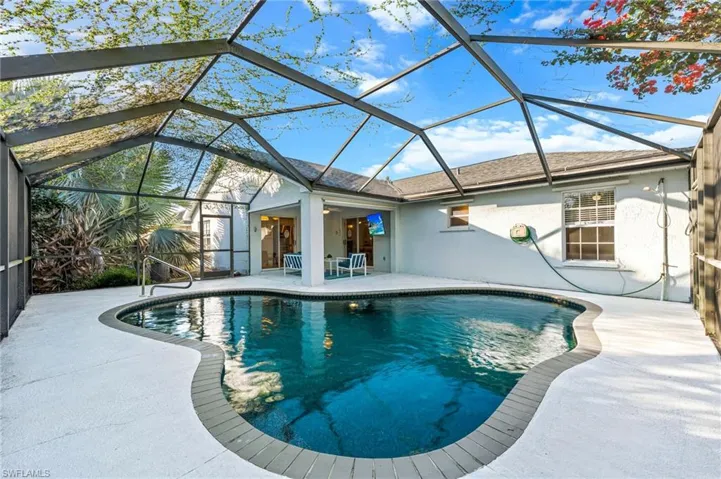 Outdoor pool featuring a sunroom, a patio, and glass enclosure