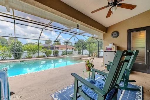 View of swimming pool featuring a patio area, glass enclosure, an in ground hot tub, and ceiling fan