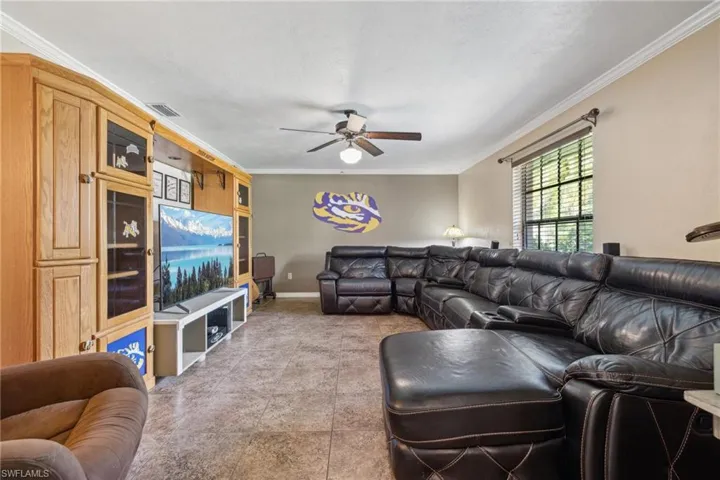 Living room with tile floors, ornamental molding, and ceiling fan