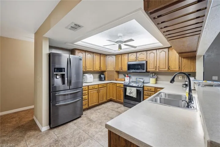 Kitchen featuring sink, ceiling fan, light tile floors, and stainless steel appliances