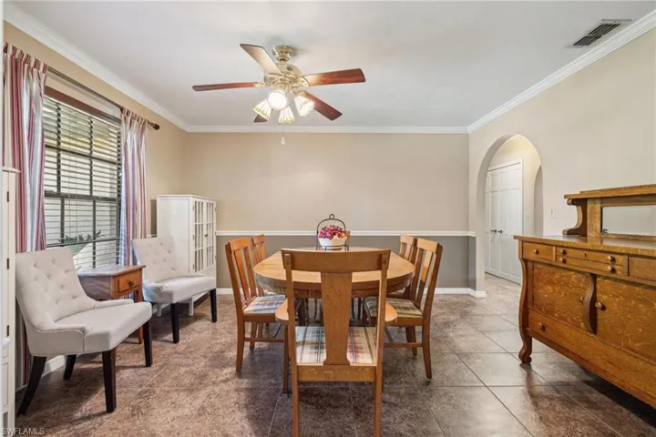 Tiled dining room with ornamental molding and ceiling fan