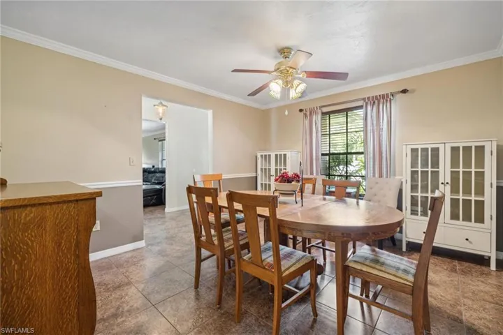 Tiled dining space with ceiling fan and crown molding