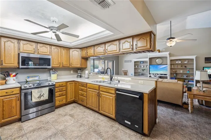 Kitchen with ceiling fan, kitchen peninsula, stainless steel appliances, light tile flooring, and sink