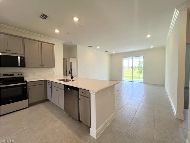 Kitchen with appliances with stainless steel finishes, gray cabinets, light tile patterned flooring, ornamental molding, and a peninsula