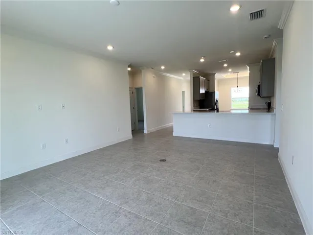 Unfurnished living room with light tile patterned flooring, crown molding, and recessed lighting