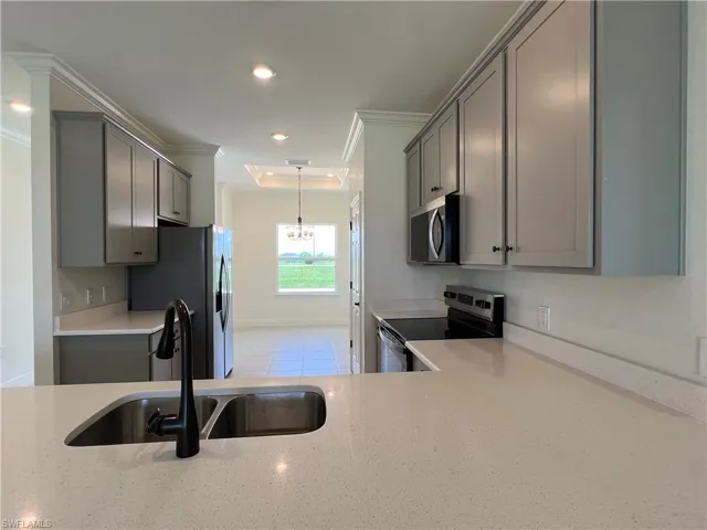 Kitchen featuring electric range, stainless steel microwave, gray cabinets, crown molding, and fridge with ice dispenser