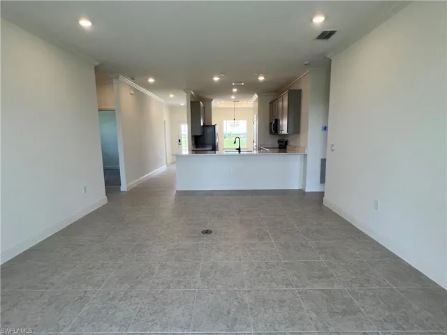 Unfurnished living room featuring crown molding, recessed lighting, and light tile patterned flooring