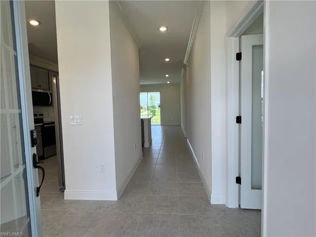 Corridor featuring crown molding, light tile patterned flooring, and recessed lighting