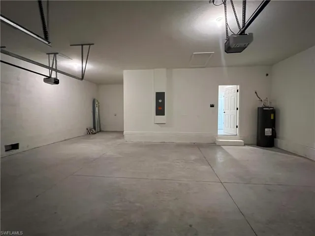 Garage with a garage door opener, water heater, and electric panel