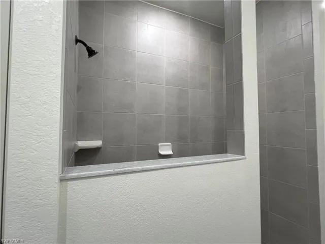 Bathroom featuring a walk in shower and a textured wall