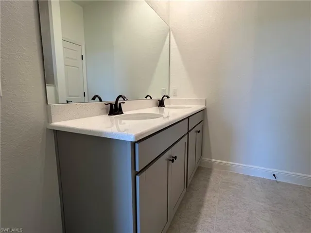 Full bath with double vanity and baseboards