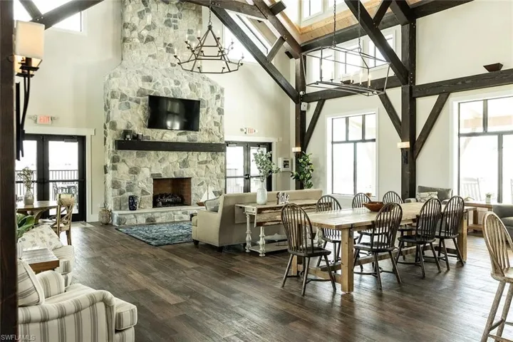 Great room featuring a floor-to-ceiling stone fireplace, exposed timber beams, and wood-finish flooring
