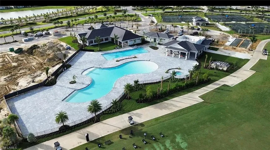 Expansive resort-style pool area featuring a freeform swimming pool, integrated spa, and extensive paved decking