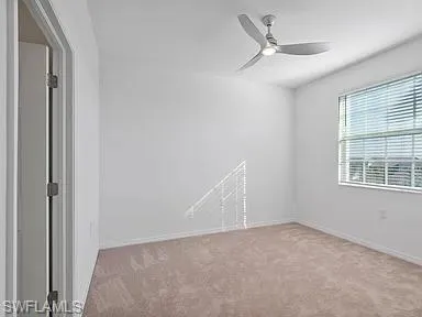 Carpeted interior room with white walls, a single window with horizontal blinds, and a ceiling fan with integrated lighting