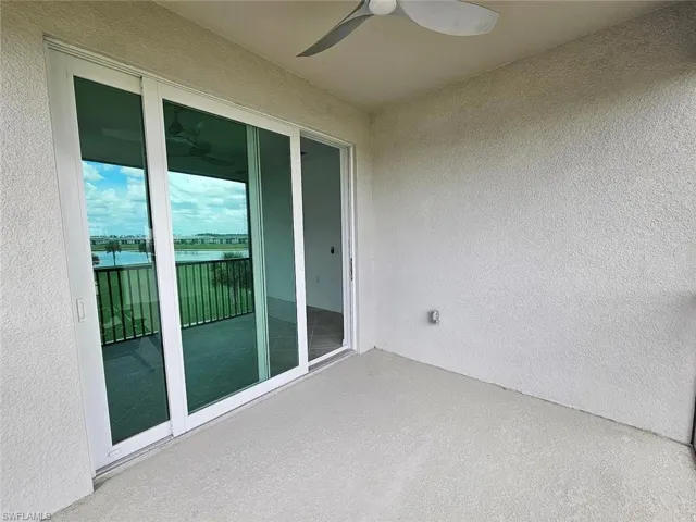 Outdoor balcony featuring a concrete floor, textured stucco walls, and a ceiling fan