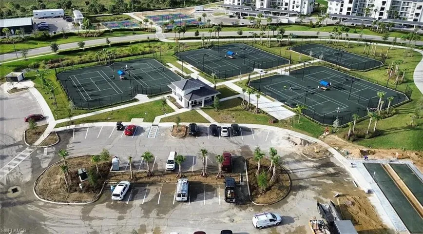 Multiple hard-surface tennis courts featuring perimeter fencing and a central pavilion building