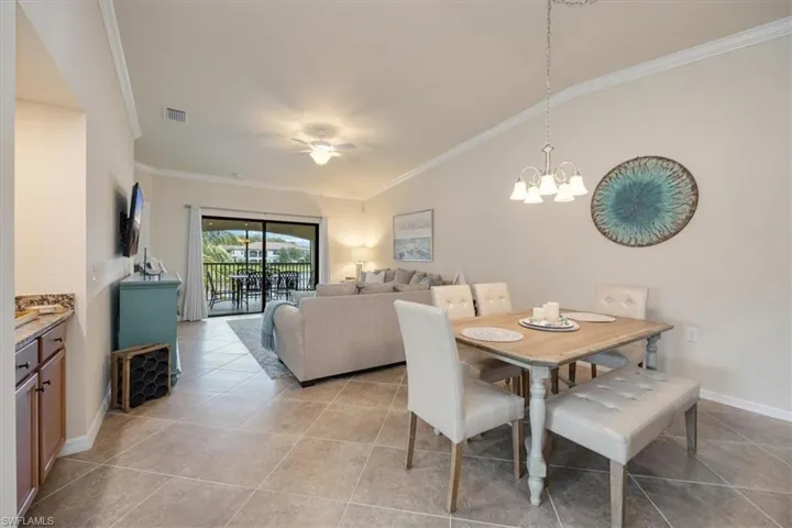 Dining room with crown molding, light tile patterned flooring, and a notable chandelier