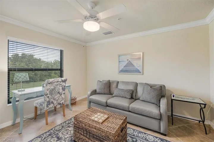 Living room featuring crown molding, ceiling fan, and tile patterned floors