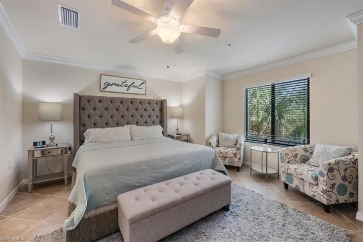 Tiled bedroom featuring ceiling fan and crown molding