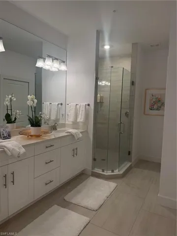 Full bathroom featuring double vanity, a stall shower, and light tile patterned flooring