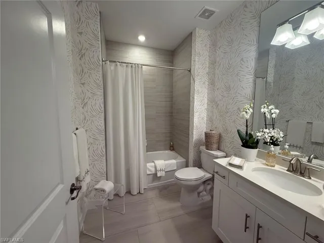 Guest Bathroom with vanity, shower / bath combo with shower curtain, wallpapered walls, light tile patterned flooring, and recessed lighting