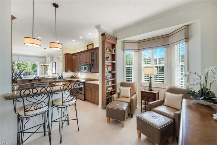 Open-concept kitchen and lounge area featuring wood cabinetry, stone countertops, and tile flooring
