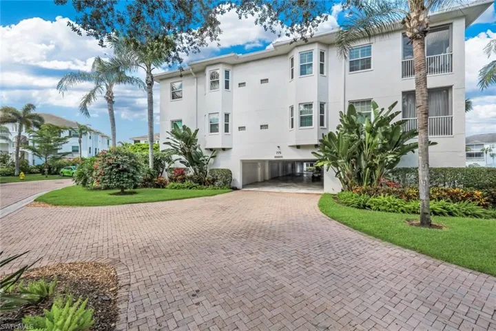 Three-story white stucco building with bay windows and a ground-level covered parking area
