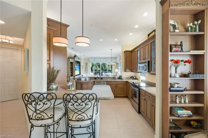Gourmet kitchen featuring wood cabinetry, granite countertops, stainless steel appliances, recessed lighting, and tile flooring