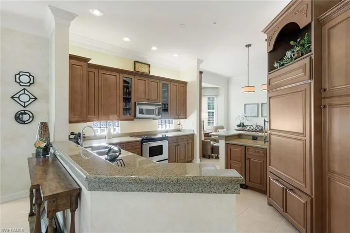 Kitchen featuring rich wood cabinetry, granite countertops, stainless steel appliances, recessed lighting, and a breakfast bar