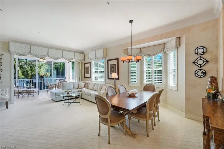 Open-concept living and dining area with textured wall finishes, crown molding, and patterned carpeting
