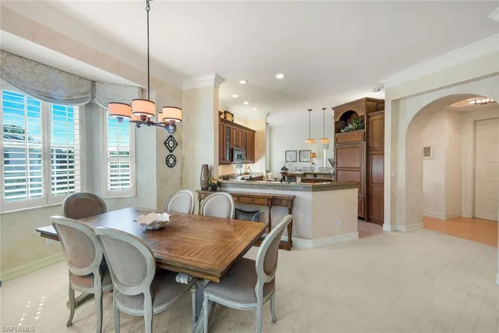 Open concept dining area with a multi-light chandelier, plantation shuttered bay windows, and light-toned flooring