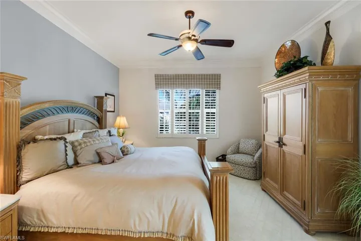Spacious room featuring crown molding, a ceiling fan with light, a window with plantation shutters, and light-colored wall-to-wall carpeting