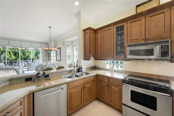 Kitchen featuring warm wood cabinetry, light-colored countertops, stainless steel appliances, and a pass-through counter area