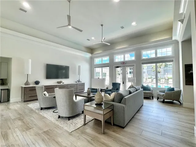 Spacious living area featuring wood-finish flooring, vaulted ceilings with contemporary ceiling fans, and large windows with transom panels