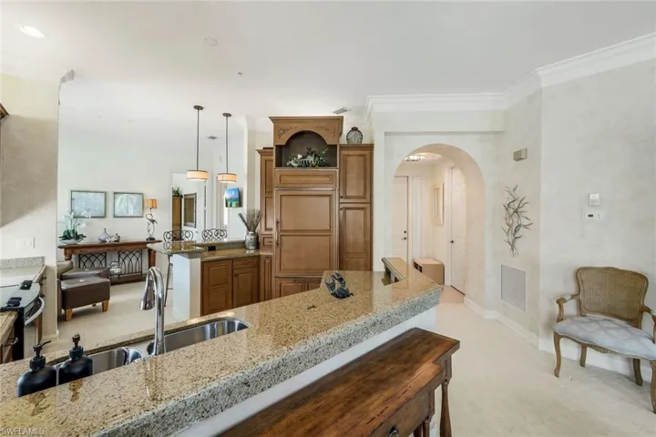 Kitchen featuring granite countertops, wood cabinetry, a stainless steel sink, and pendant lighting