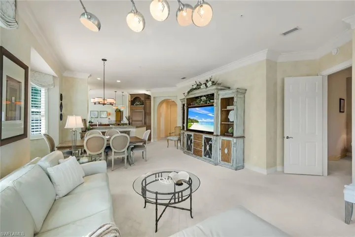 Spacious living area featuring neutral carpeting, crown molding, and recessed lighting