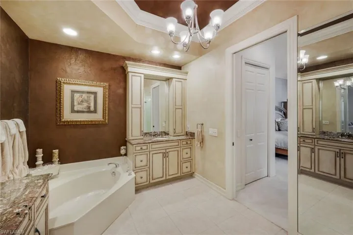 Corner garden tub with surrounding countertop and integrated sink vanity featuring extensive cabinetry