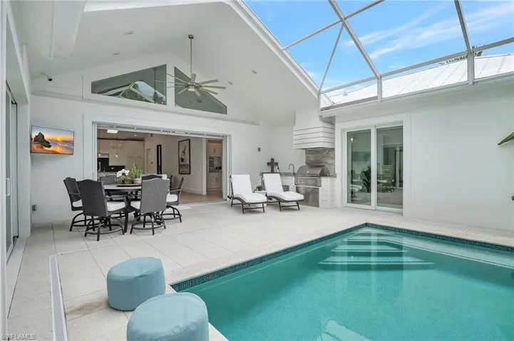 Rear view of property featuring an outdoor kitchen, ceiling fan, a patio area, stucco siding, and an outdoor pool