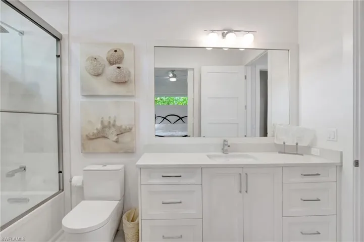 Full bathroom featuring vanity, enclosed tub / shower combo, ensuite bath, and ceiling fan