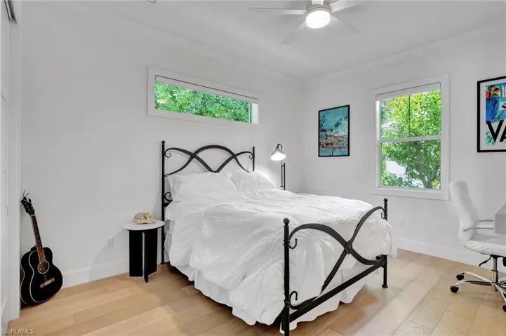 Bedroom featuring ornamental molding, multiple windows, light wood-style floors, and ceiling fan