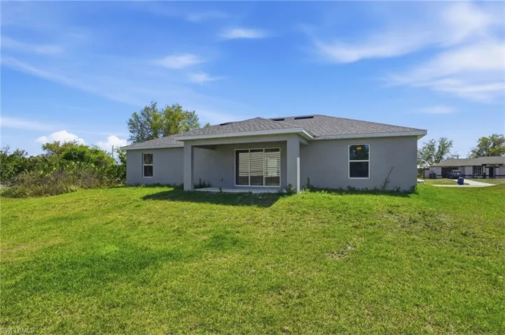 Rear view of house featuring stucco siding, a patio area, and a yard