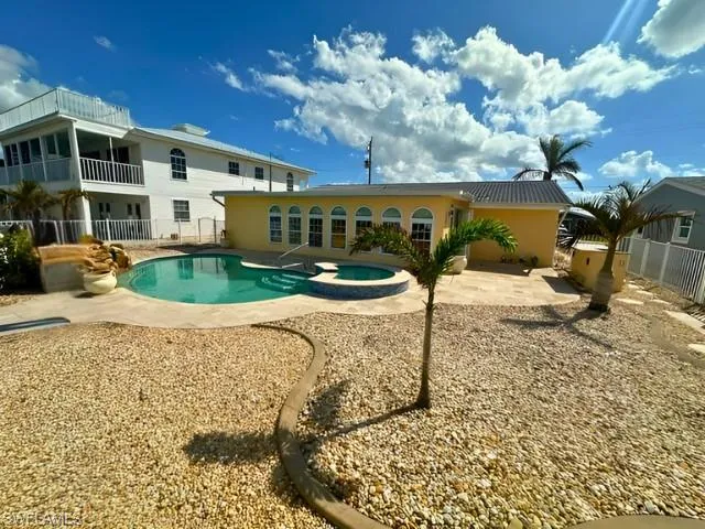 View of pool with a patio and an in ground hot tub