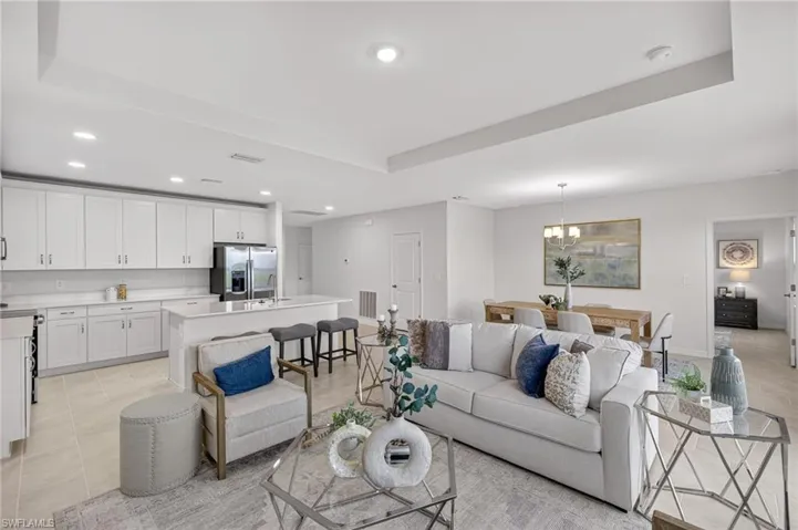 Living area with recessed lighting, a tray ceiling, light tile patterned flooring, and a chandelier
