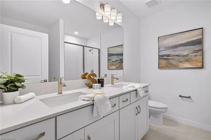 Full bathroom featuring double vanity, a stall shower, light tile patterned floors, and recessed lighting